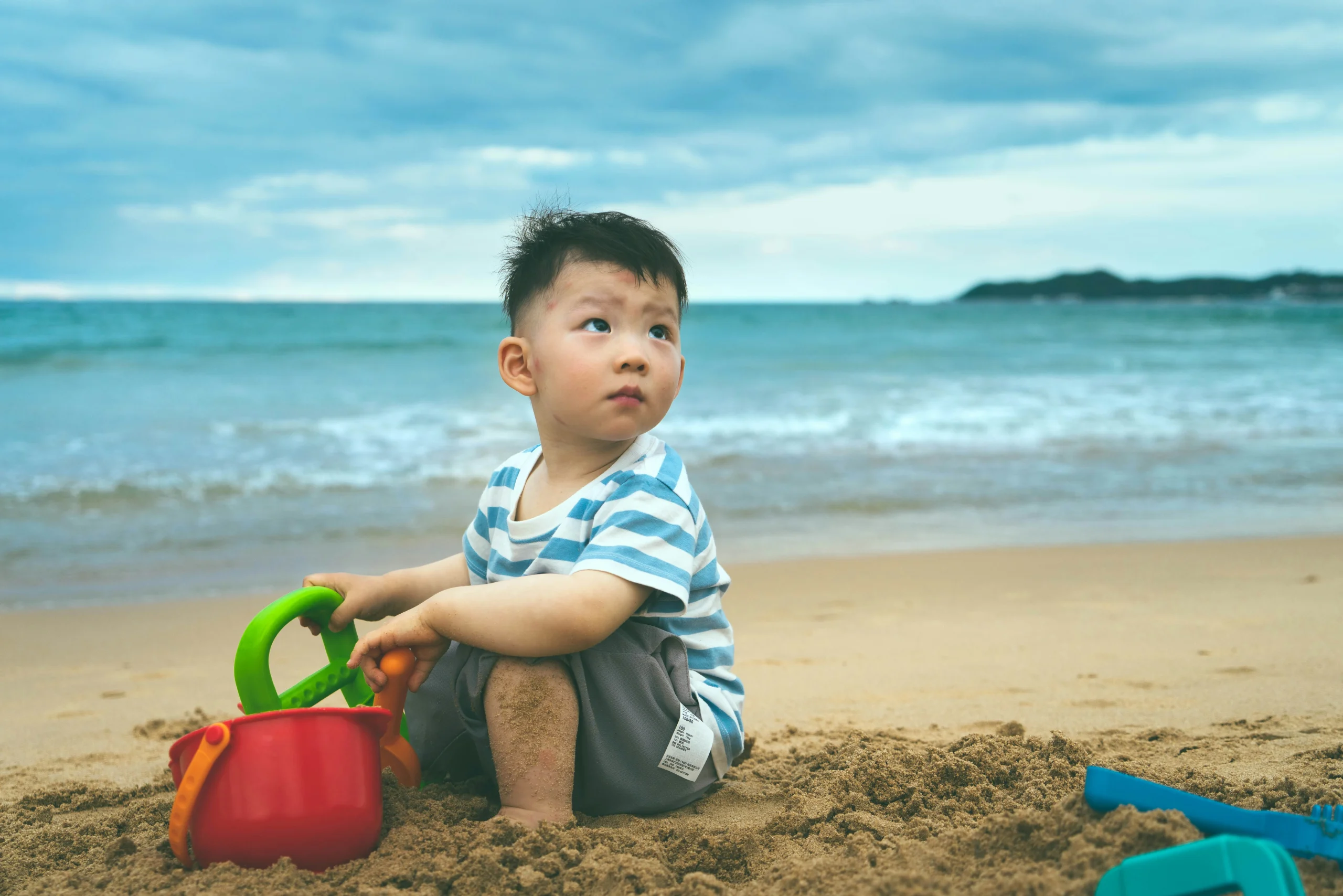boy playing with sand near sea