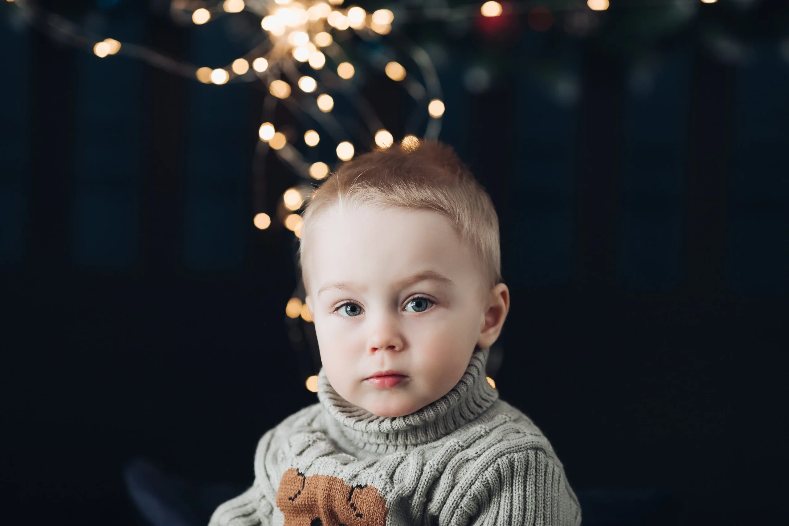 littly baby boy with christmas light in background