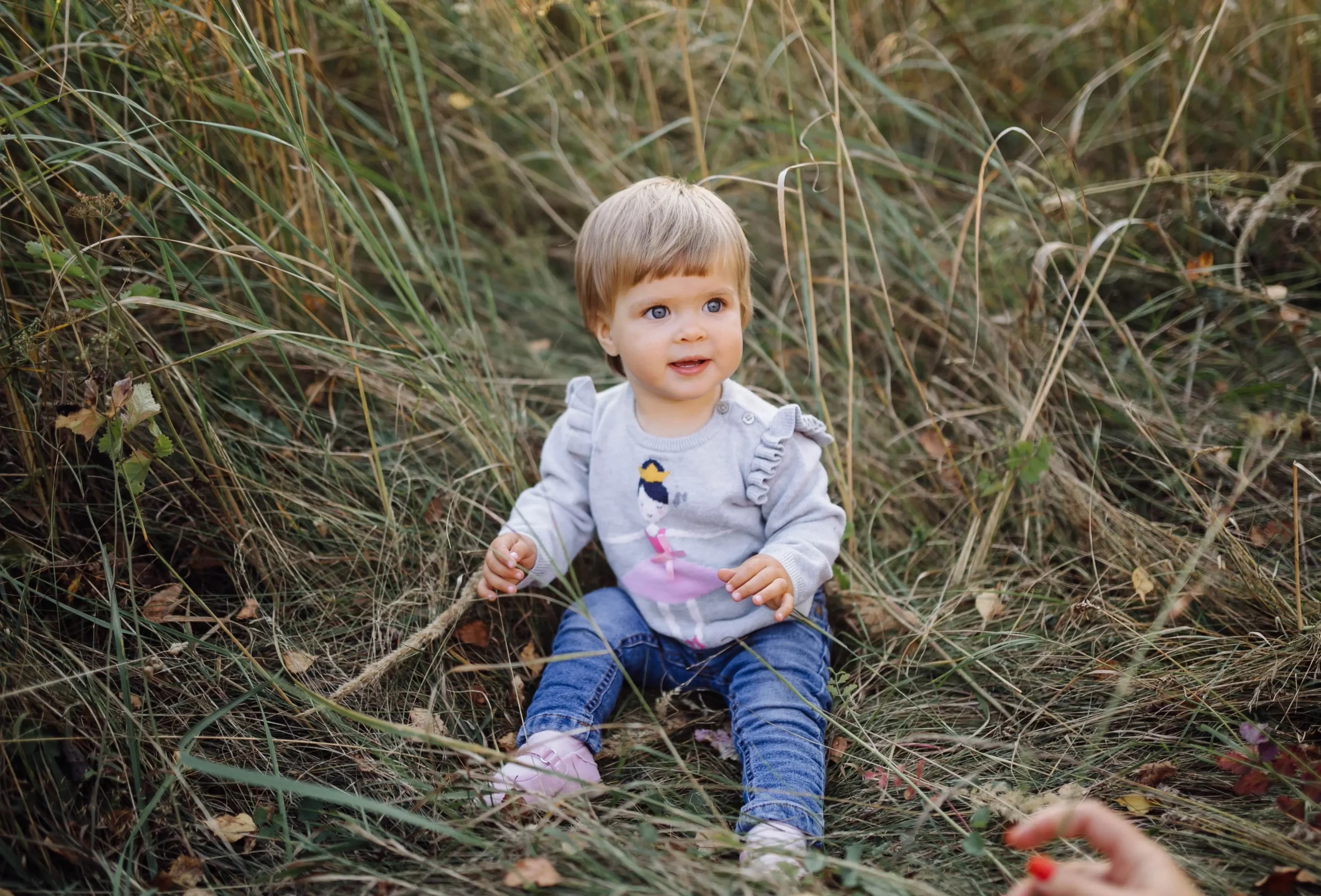 little boy sitting in meadow smiling